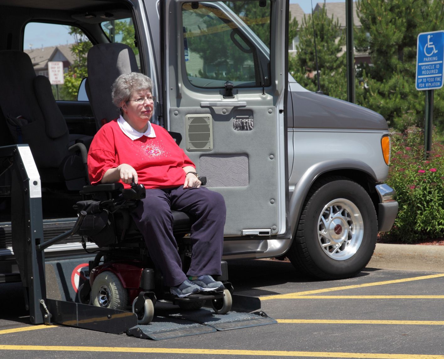 A woman in a wheelchair is getting out of a van A woman in a wheelchair is getting out of a van