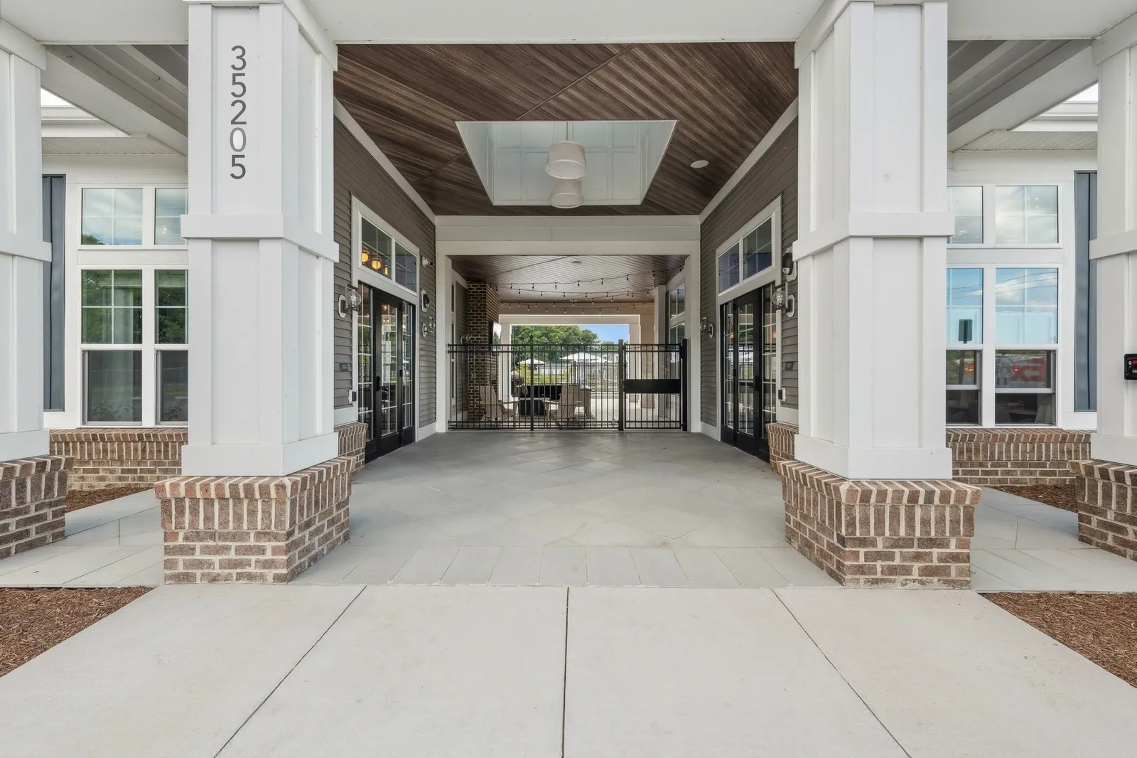 Covered community entrance with brick columns, glass doors, and a gated passage.
