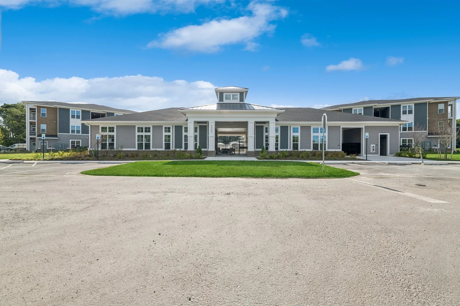 Exterior view of a modern apartment community with a central portico and landscaping.