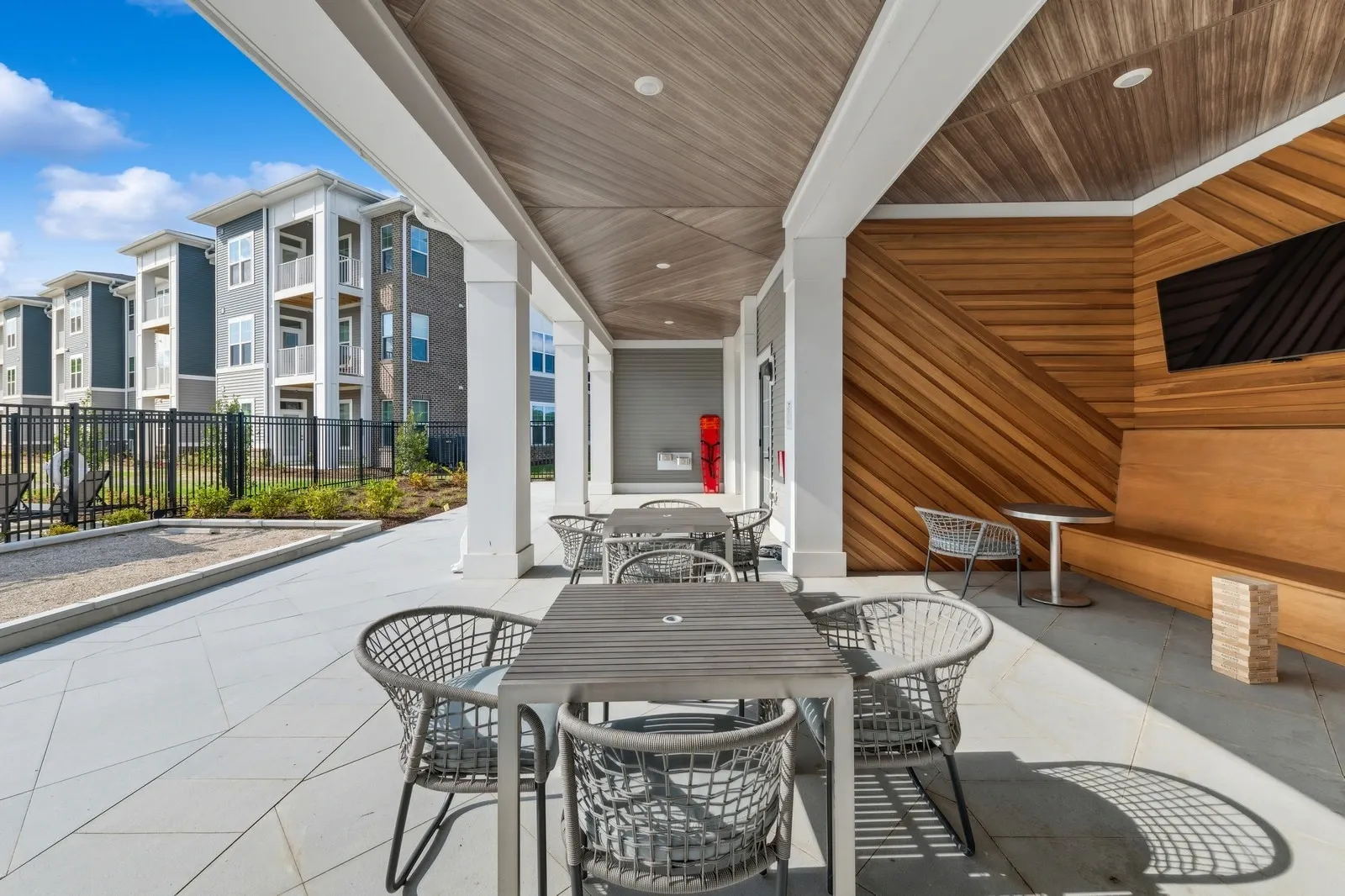 Outdoor covered courtyard with metal tables and chairs beside apartment buildings.