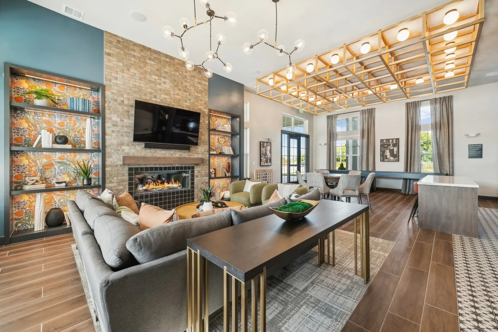 Open communal living room with sofa, fireplace, TV, shelves, and warm decor.
