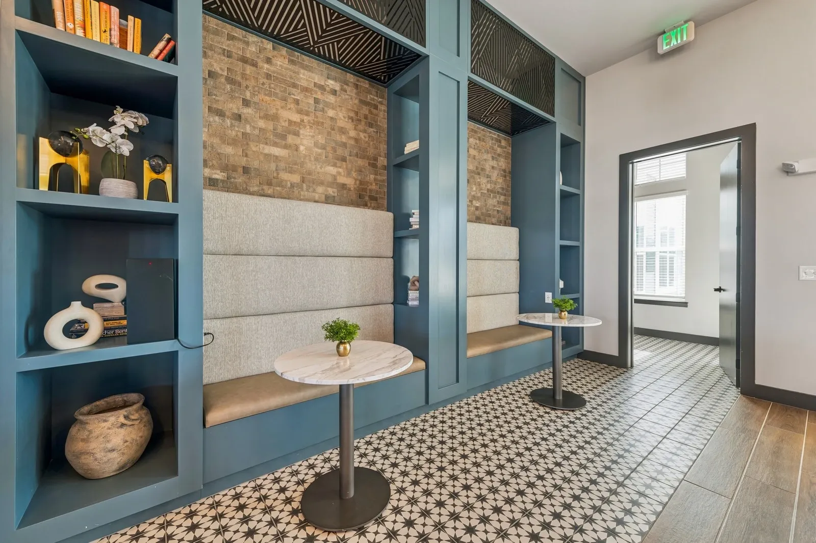 Modern lobby seating area with blue built-in shelves, beige benches, and a patterned tile floor.
