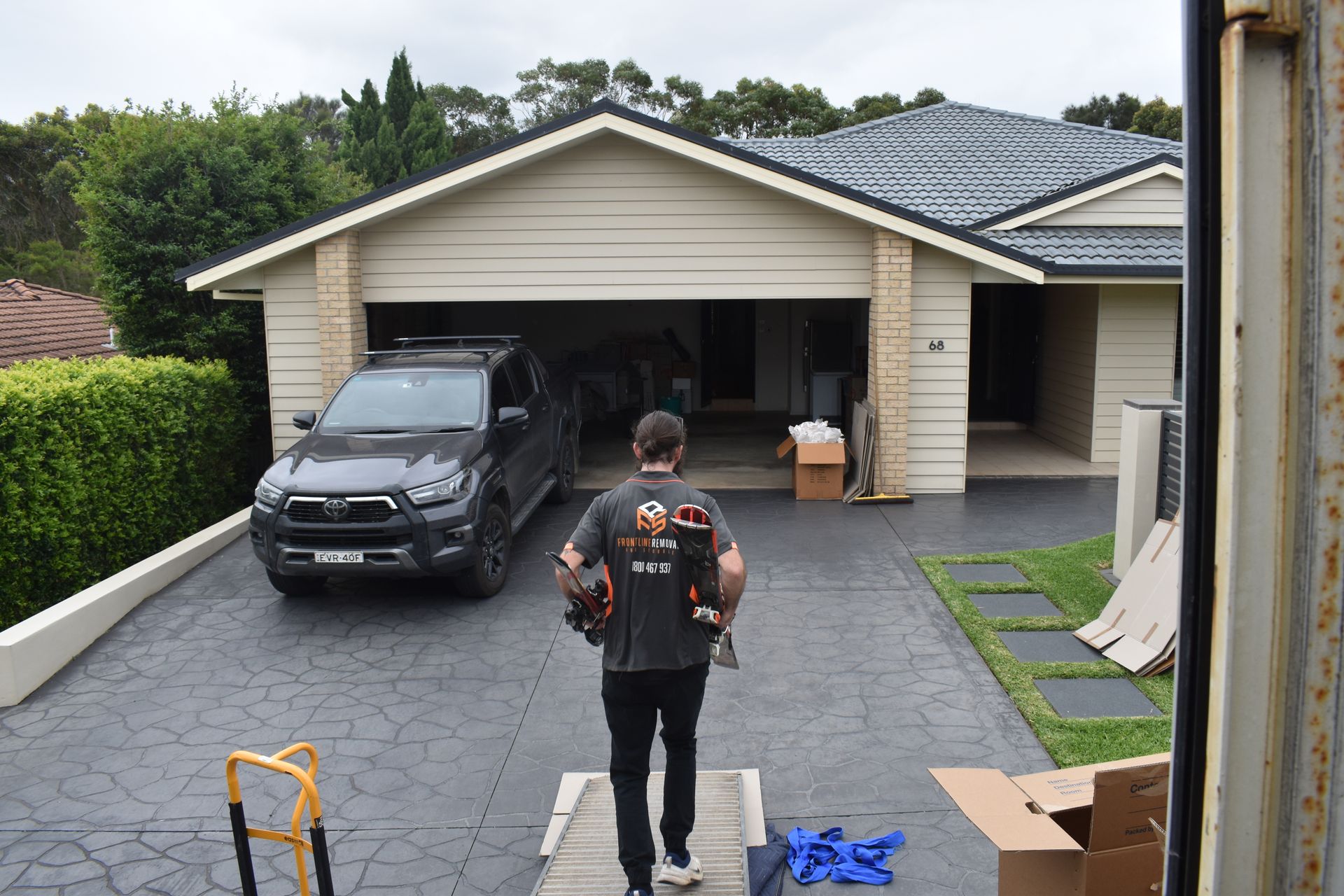 A Man Is Taping A Box With Tape — Frontline Removals And Storage in Canberra, ACT