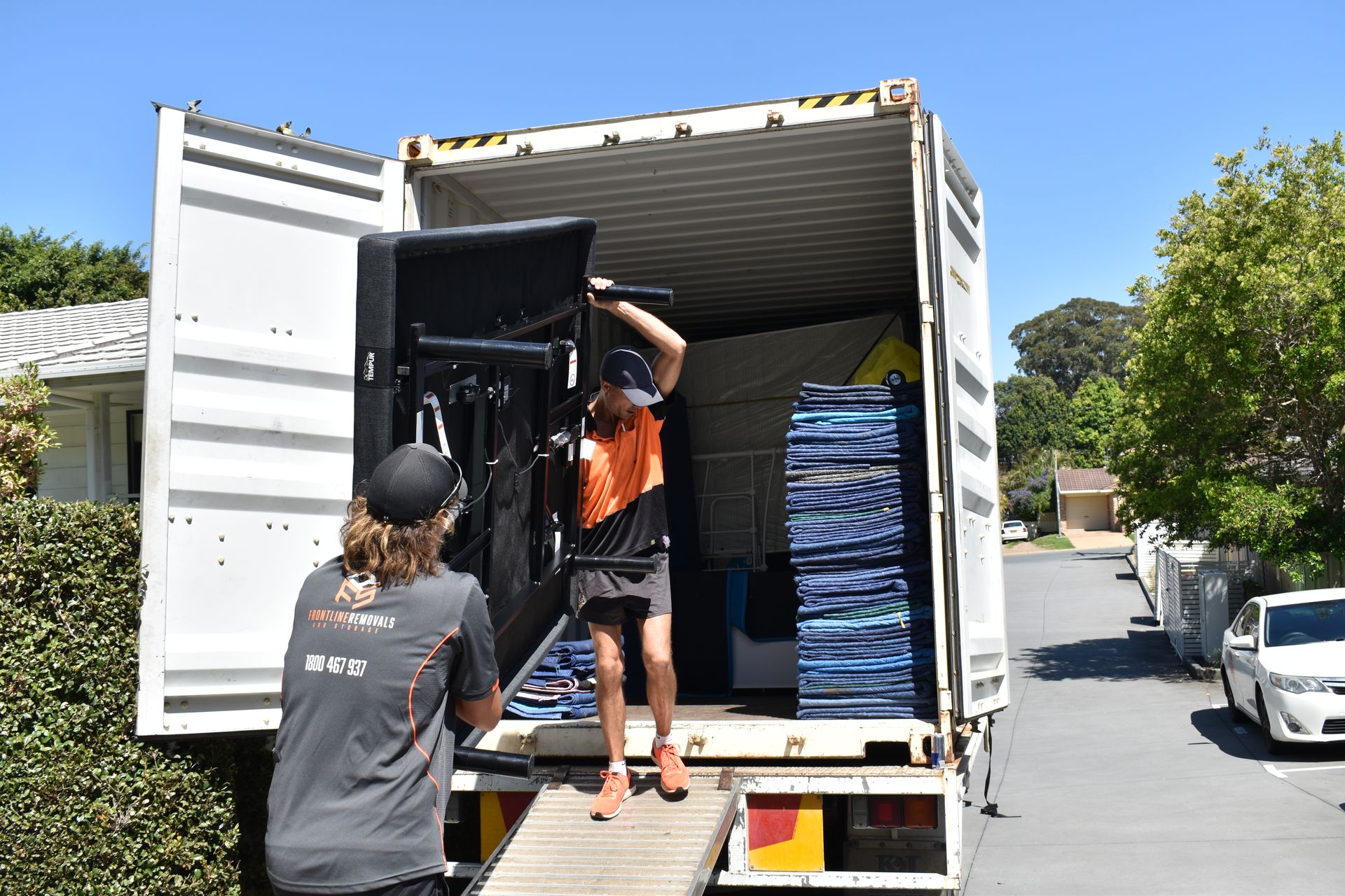 A Man And A Woman Are Seated On The Floor, Arranging Items In Boxes — Frontline Removals And Storage in Port Macquarie, NSW