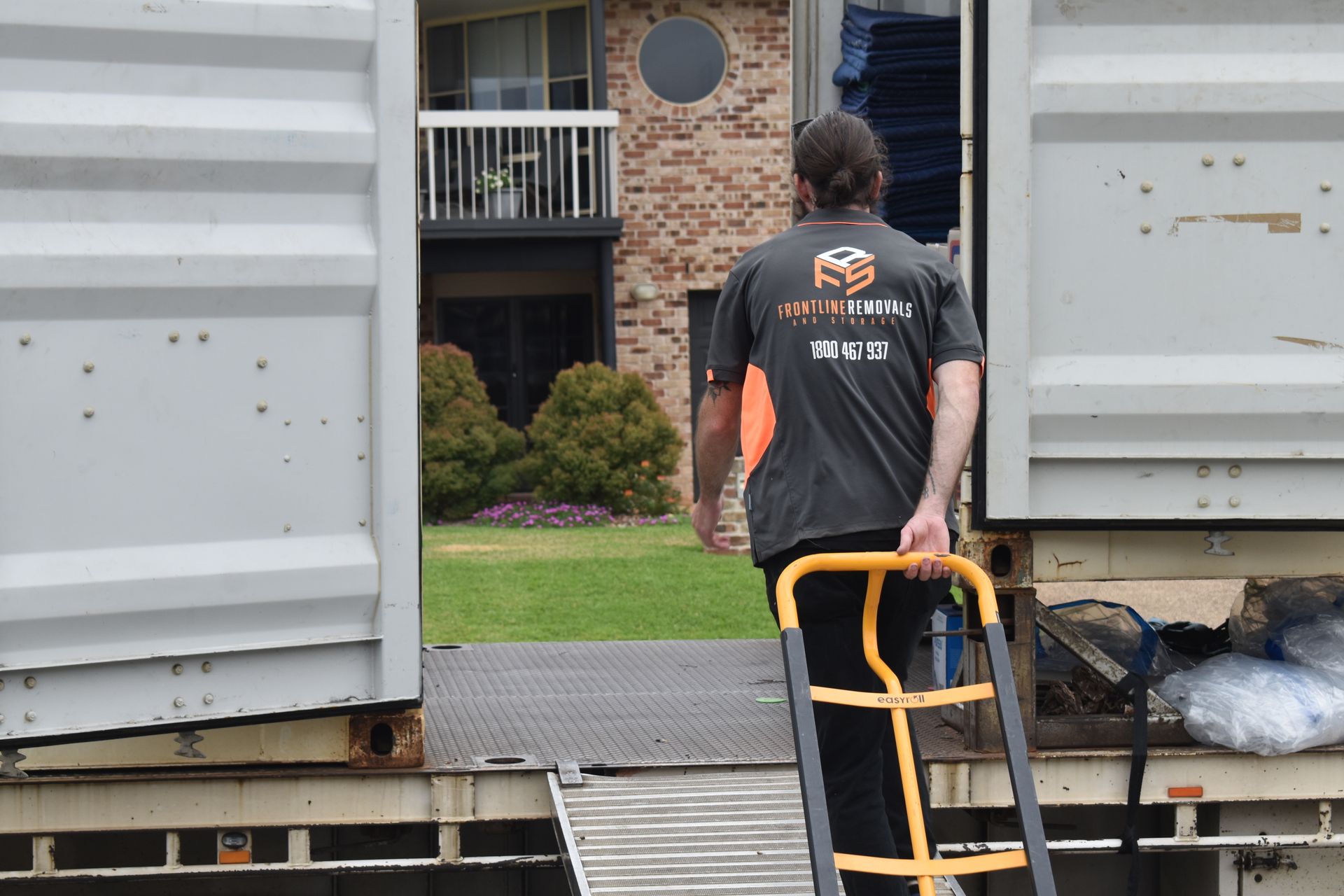 A Room Filled With Furniture And Boxes Wrapped In Blue Plastic — Frontline Removals And Storage in Maitland, NSW