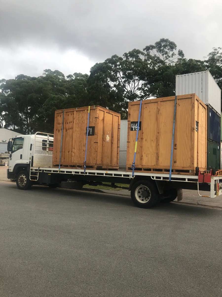 A Truck Is Carrying Wooden Crates On The Back Of It — Frontline Removals And Storage in Armidale, NSW