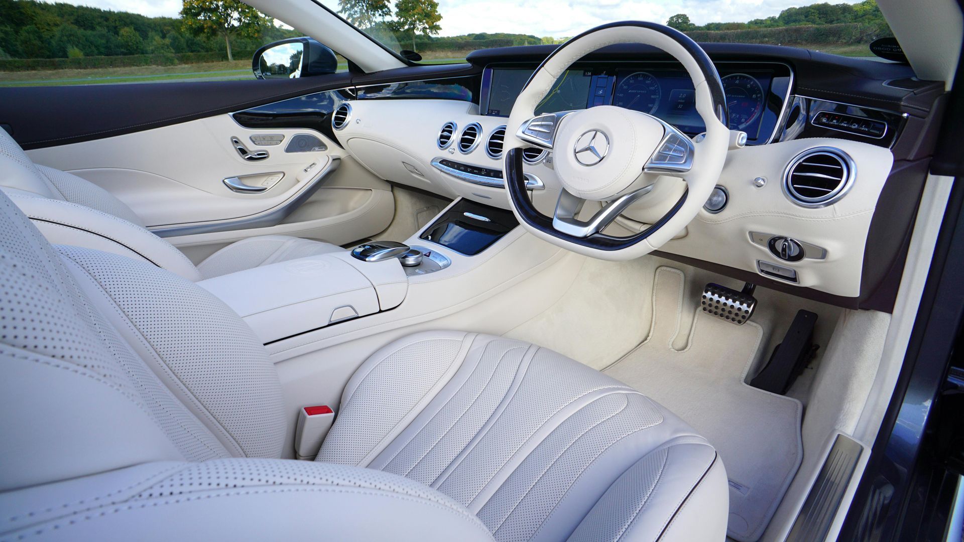 The interior of a car with white seats and a steering wheel.