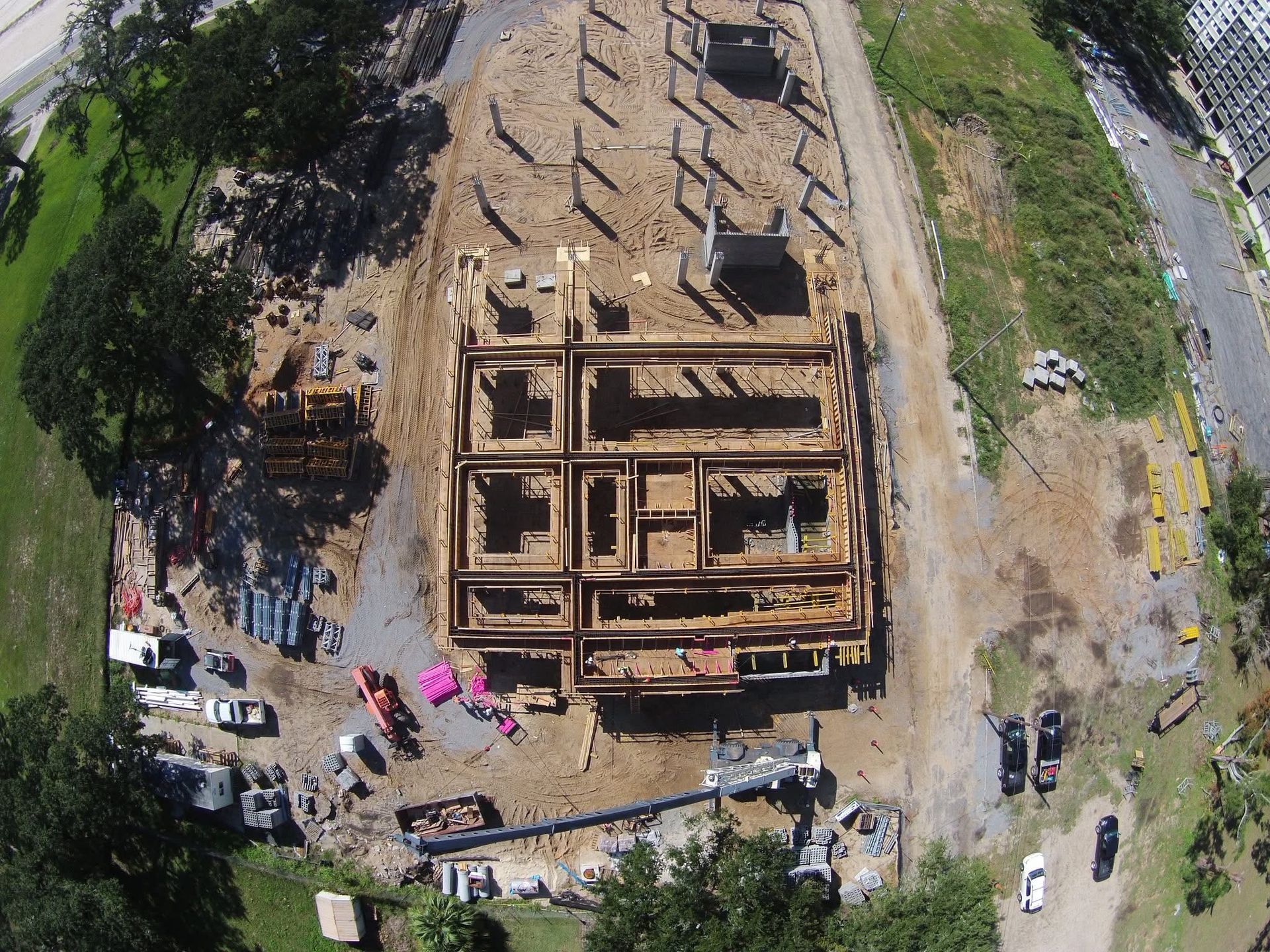 Aerial view of a large wooden building frame under construction, with workers and vehicles around it.
