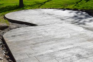Curved concrete walkway with a smooth white surface beside grass and gravel