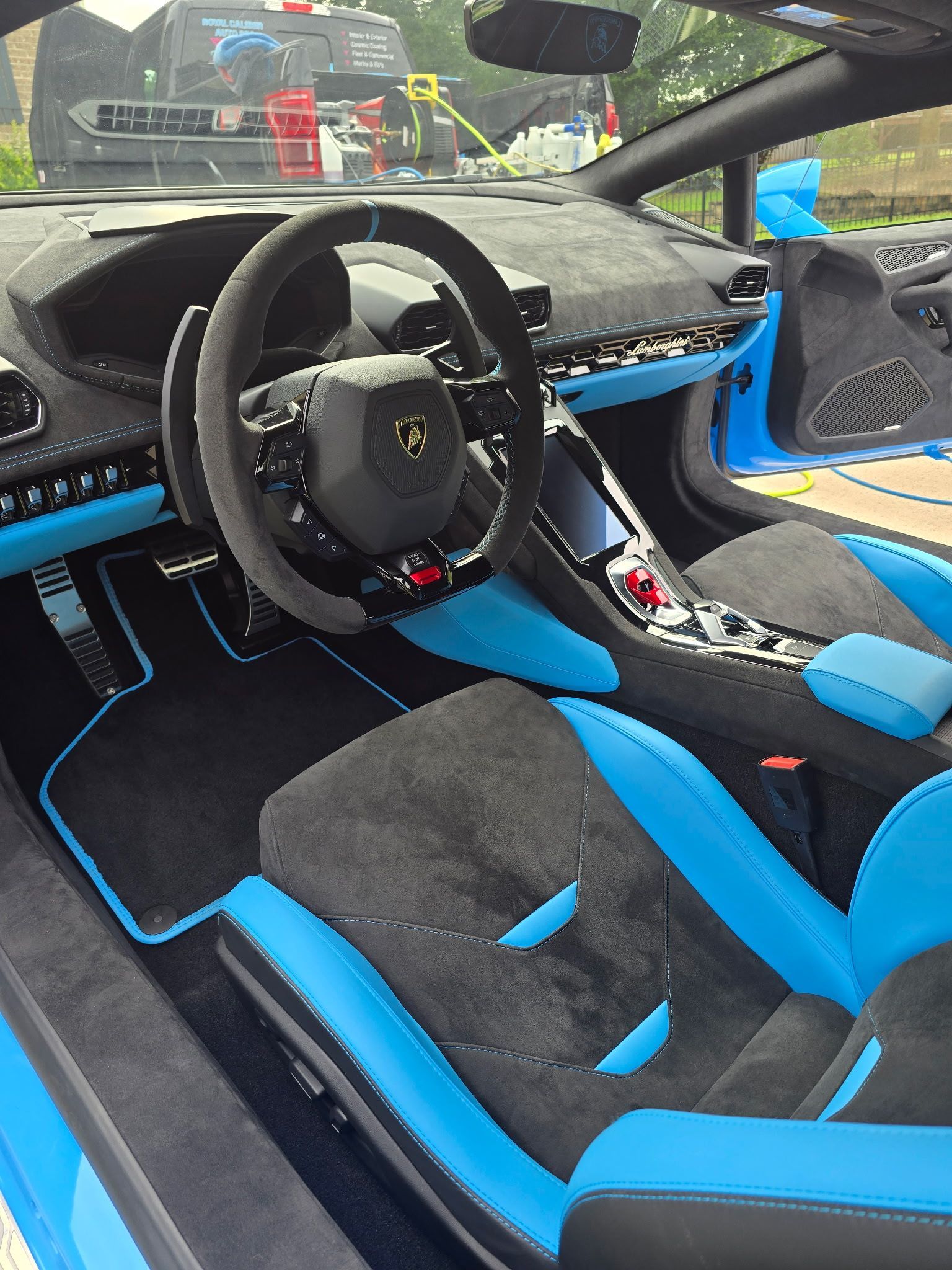 Interior of a bright blue and charcoal-gray sports car, featuring a sleek, modern dashboard and racing-style bucket seats.
