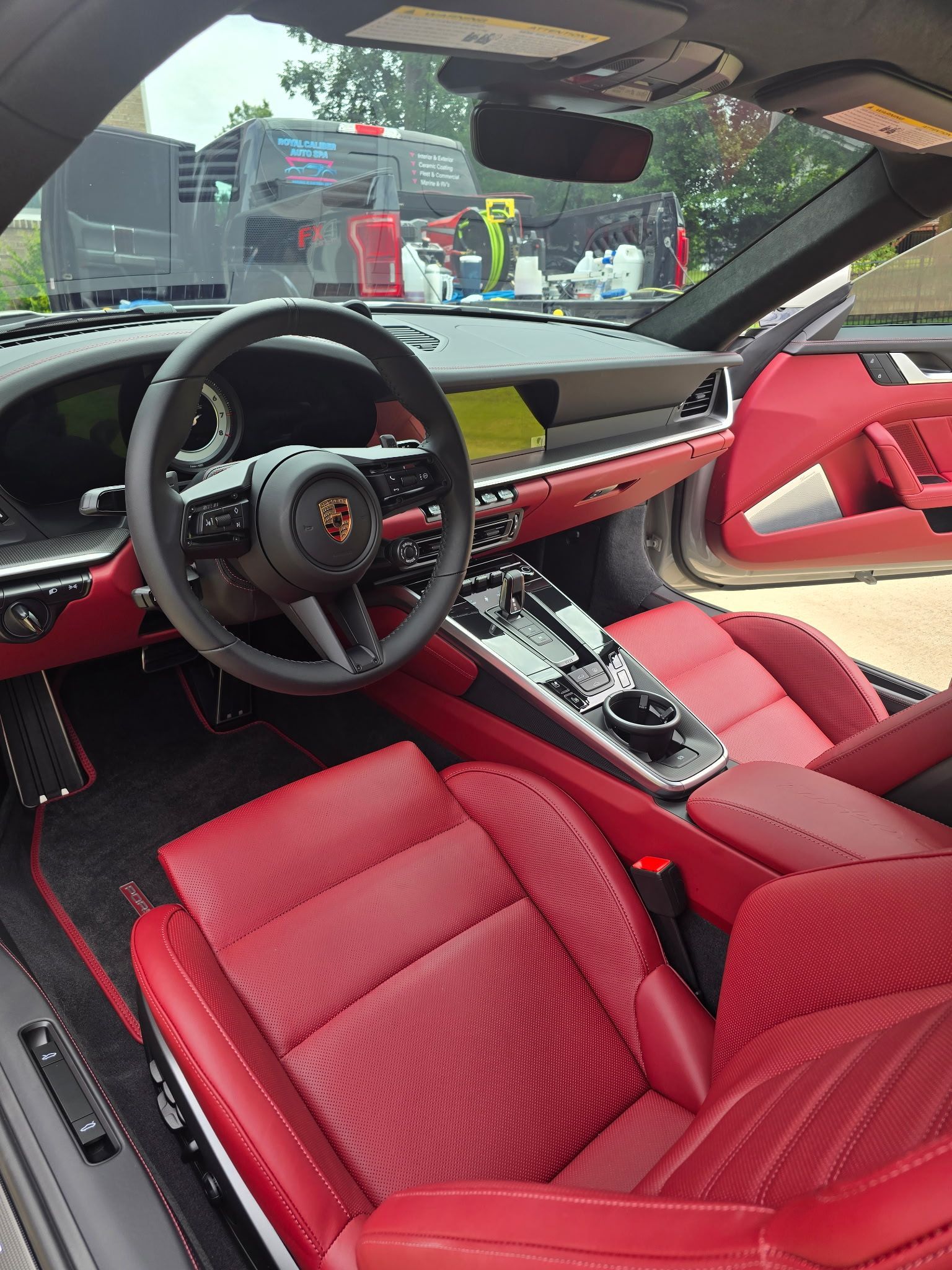 Luxury car interior featuring bright red leather bucket seats, a matching dashboard, and a black steering wheel.