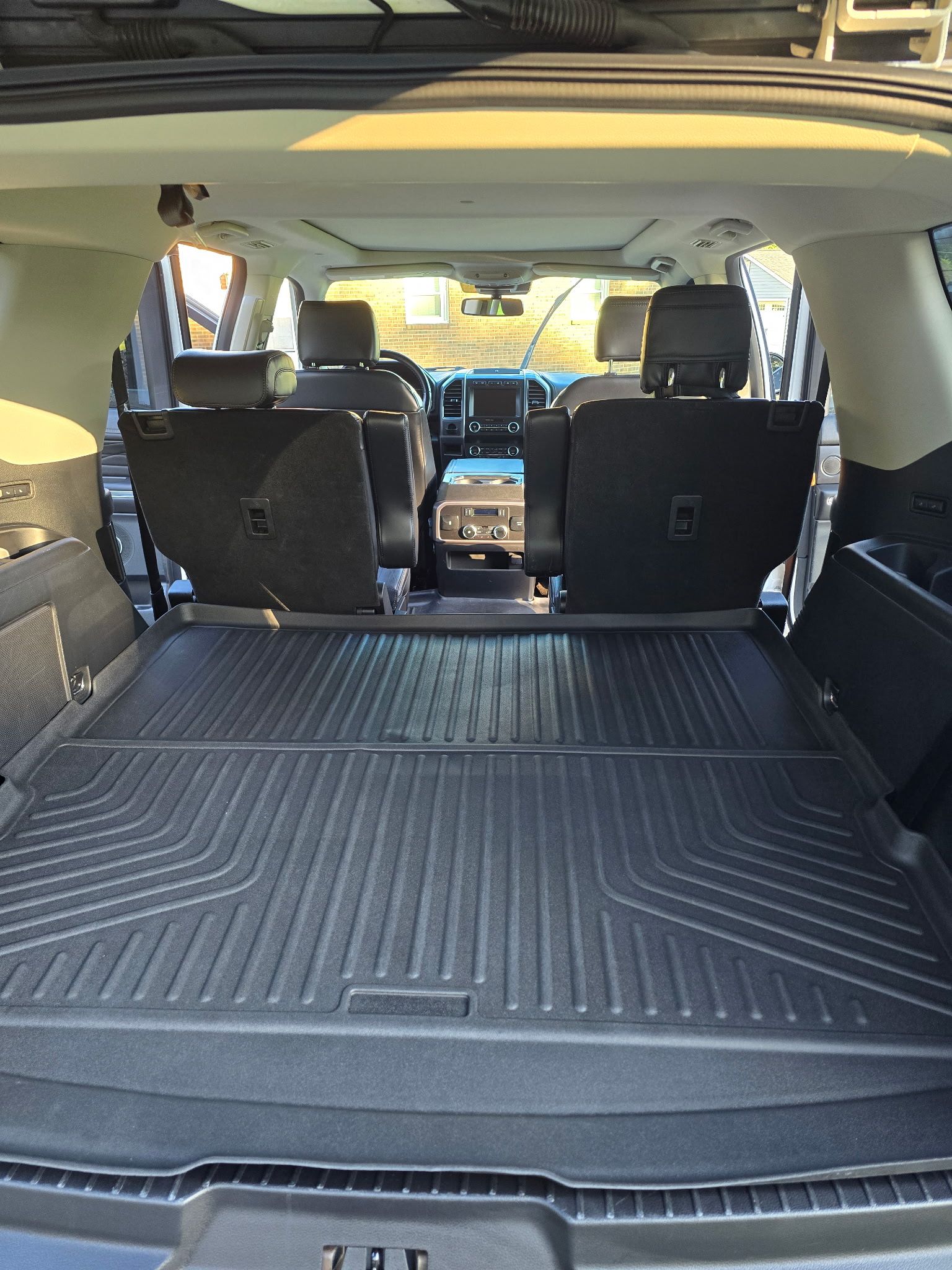 The trunk area of an SUV featuring a black rubber cargo mat, with the second row of seats visible in the background.
