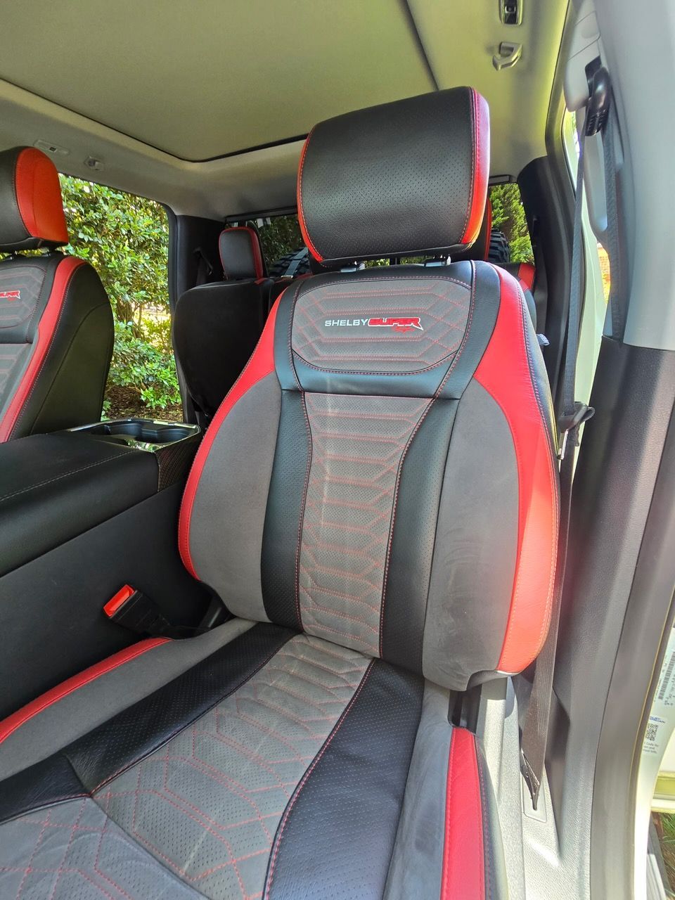 A vehicle interior featuring black and red bucket seats with a patterned gray center panel and headrests.