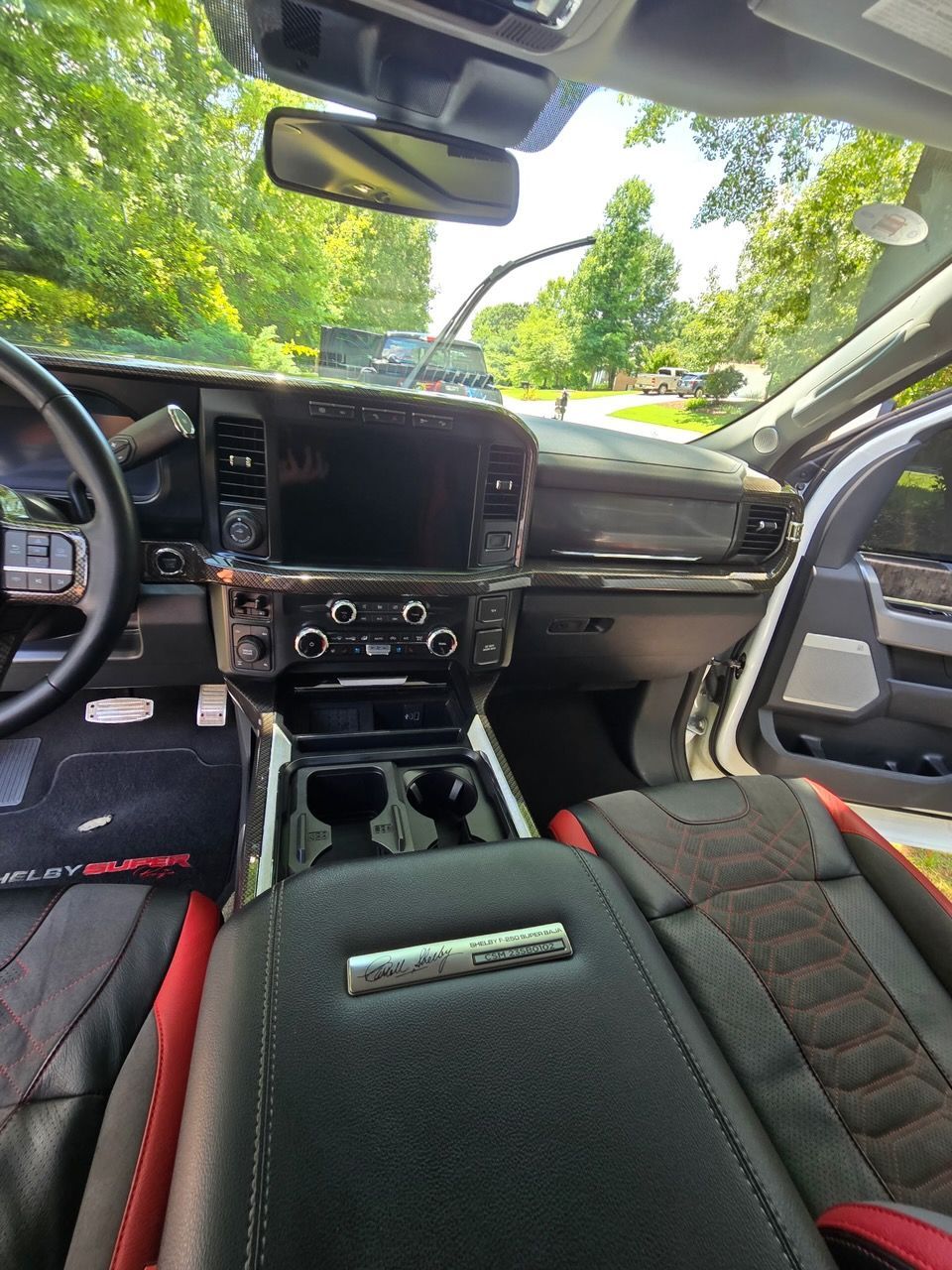 Interior view of a truck cabin featuring a dashboard, central console, and black seats with red accents.