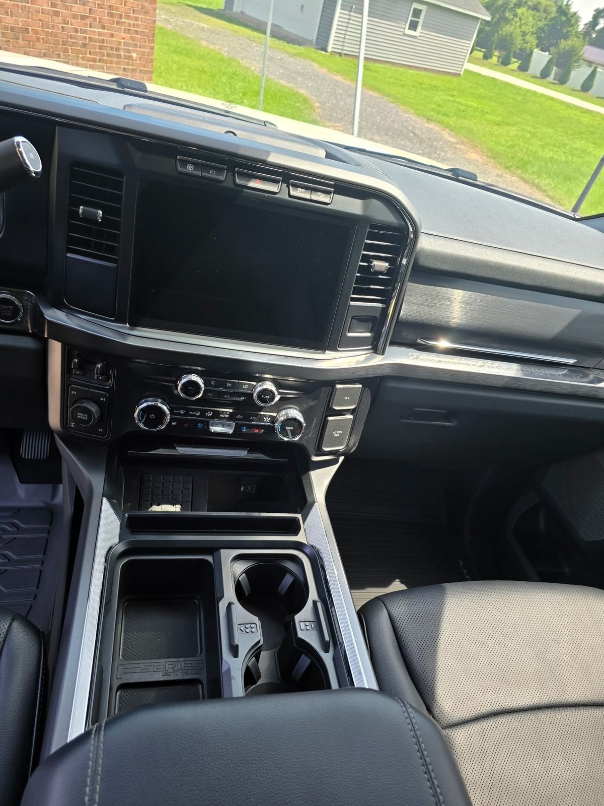 Interior view of a modern truck dashboard featuring a center touchscreen, climate controls, and a cup holder console.