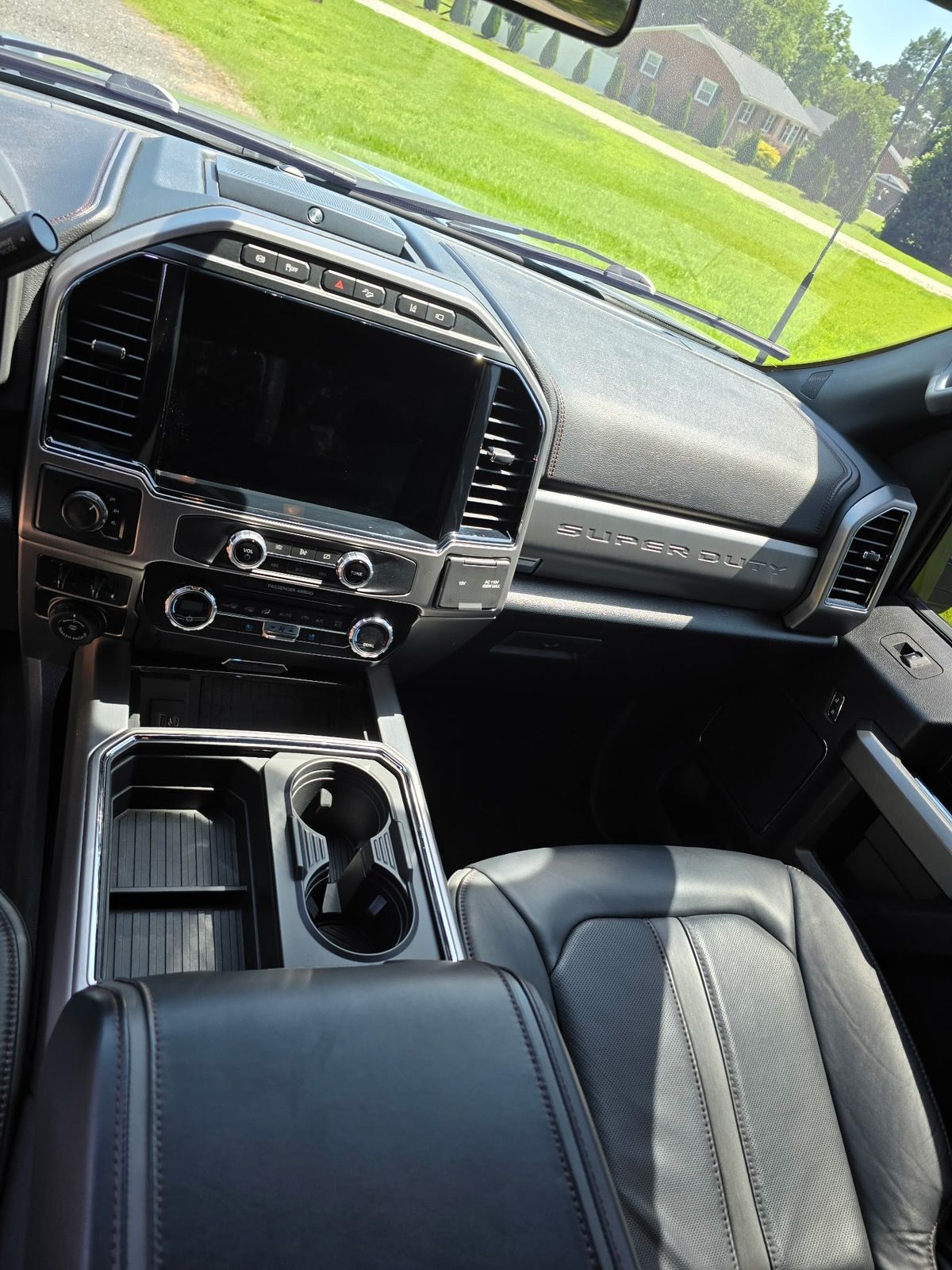Interior view of a modern truck cabin, showing a large infotainment screen, center console, and black leather seats.