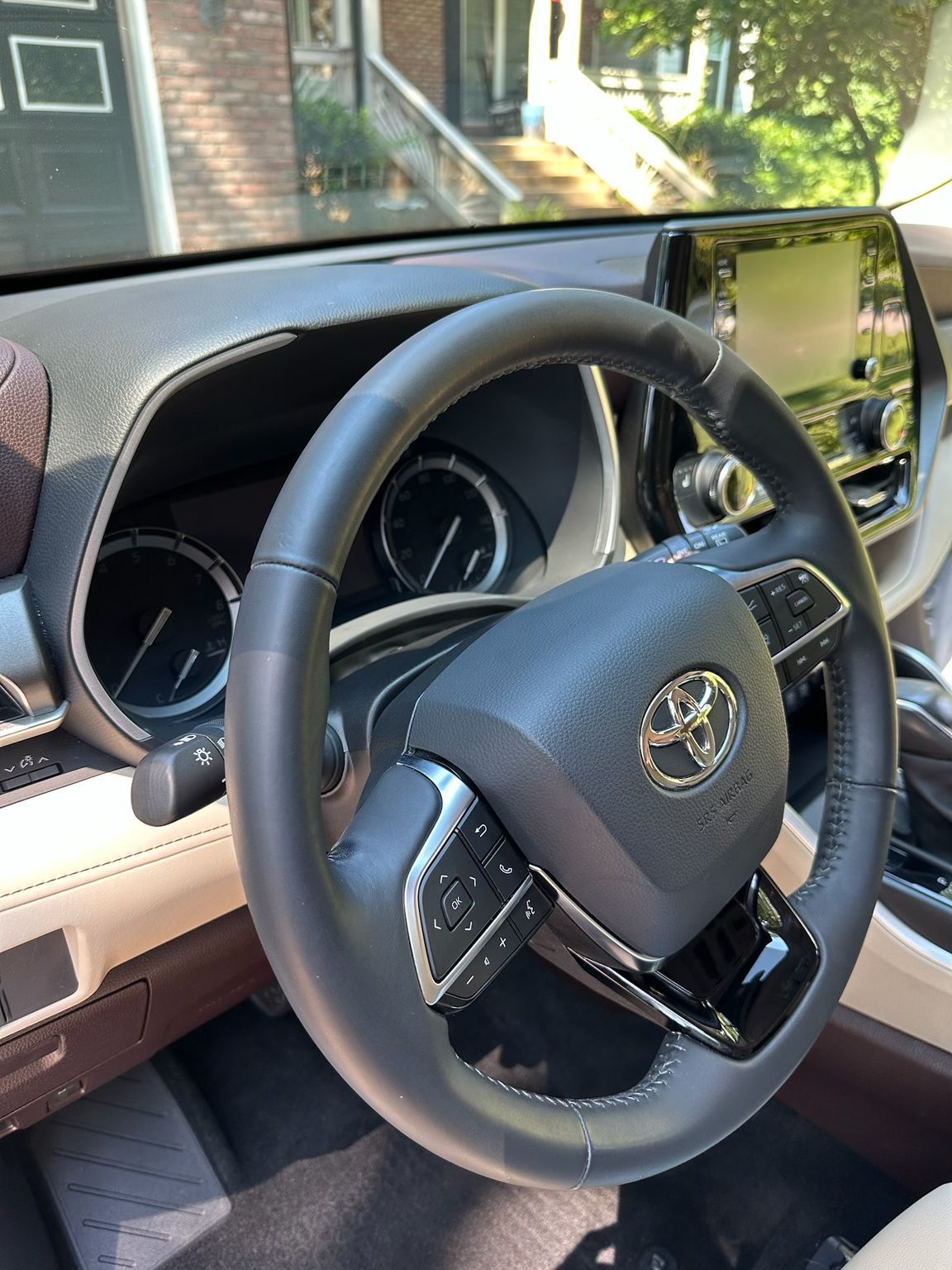 The interior of a modern Toyota vehicle showing the steering wheel, digital dashboard, and infotainment screen.