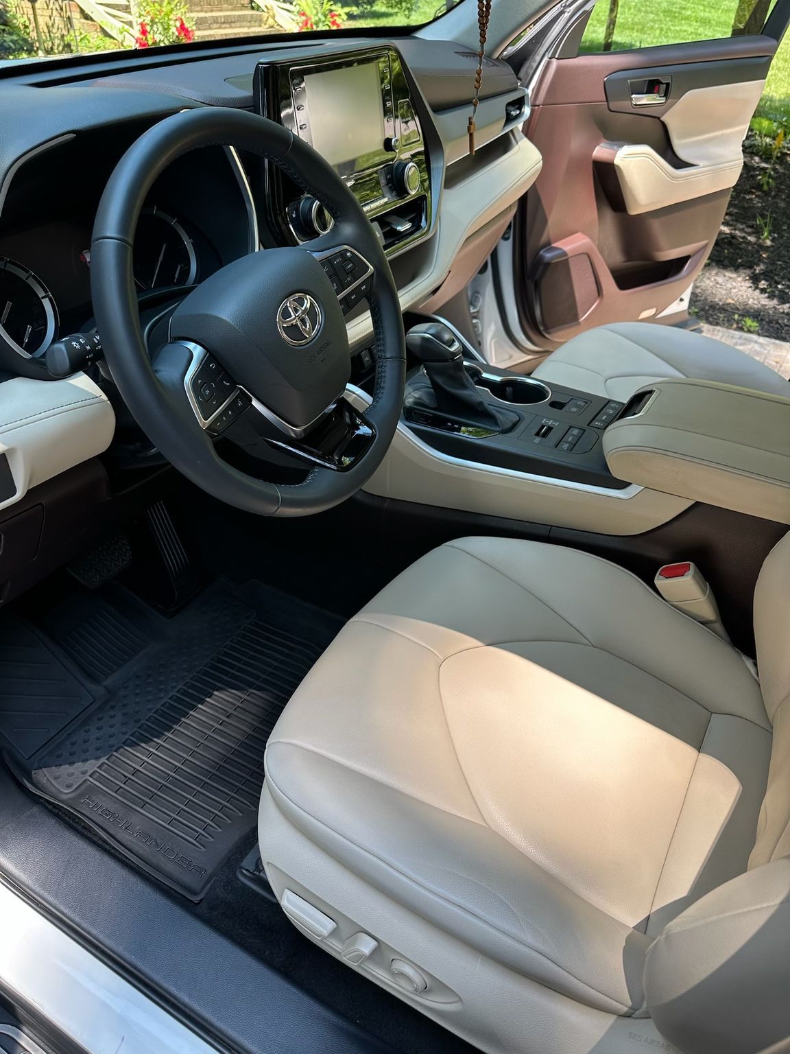 The interior of a modern Toyota vehicle with light beige leather seats, a black steering wheel, and a touchscreen display.