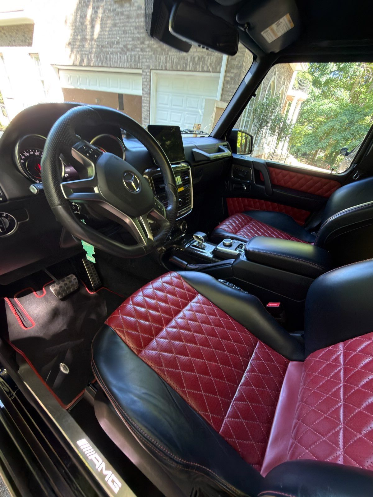 Interior of a vehicle with red-and-black diamond-stitched seats and a black steering wheel