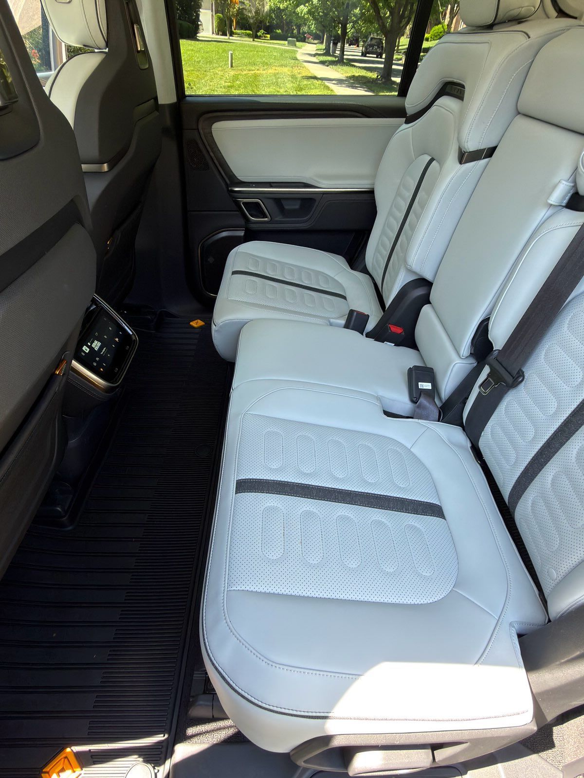 Clean white car interior with three rear seats and black floor mats, viewed from the side