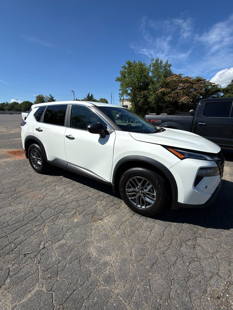 White SUV parked in a sunny outdoor lot under a clear blue sky