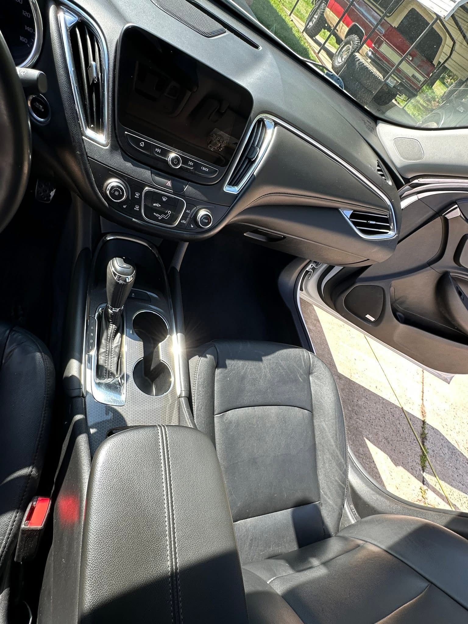 A high-angle view of a modern car interior showing the dashboard, infotainment screen, gear shifter, and front seats.