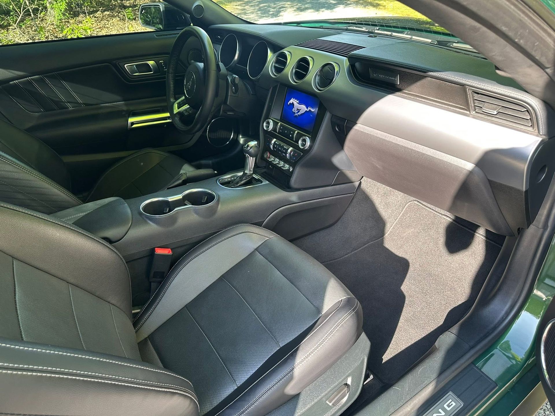 The interior of a black Ford Mustang, featuring leather bucket seats, a dashboard with circular vents, and a digital display.