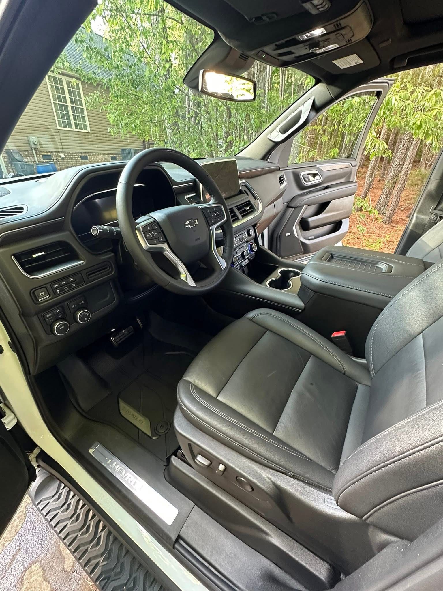 Interior view of a black leather car cabin with an illuminated digital dashboard and steering wheel.