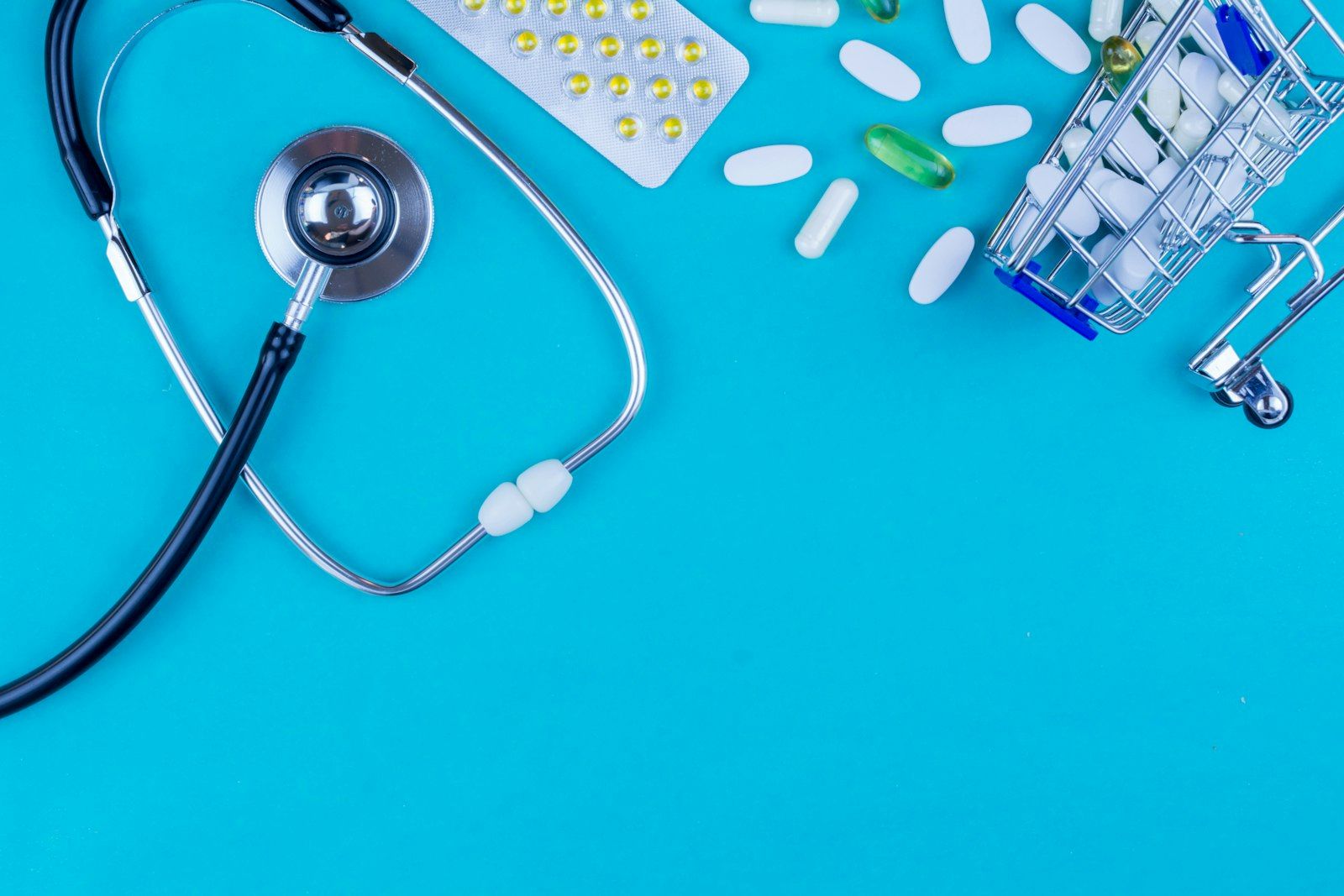 Stethoscope, pills and a shopping cart representing healthcare costs