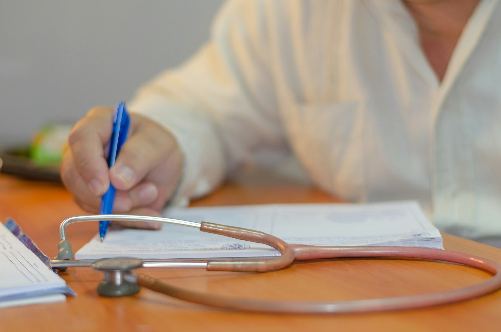 Doctor writing notes next to a stethoscope