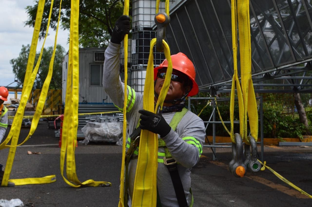 Garra de izaje sujetando placa metálica en instalación industrial