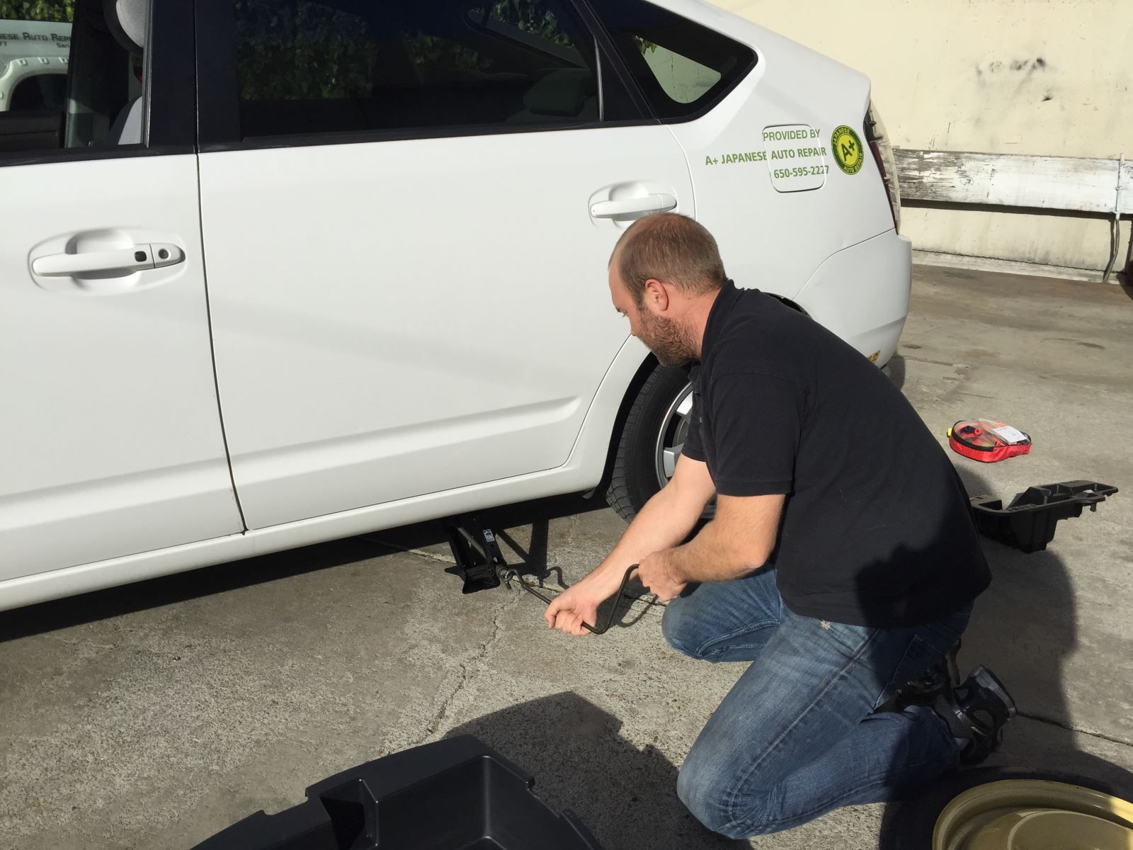 Person adjusting car jack | A+ Japanese Auto Repair, Inc.