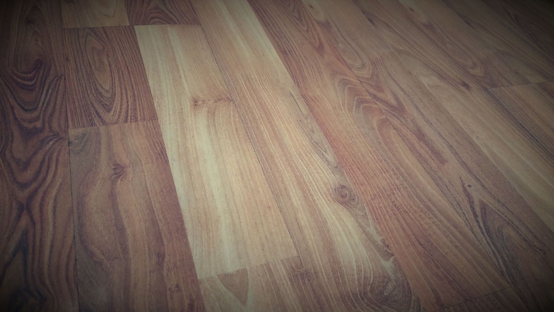 Wooden plank floor with mixed light and dark brown tones under soft lighting.