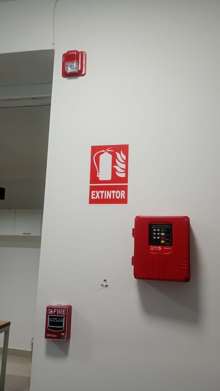 Pared con dispositivos rojos de alarma contra incendios y un letrero de