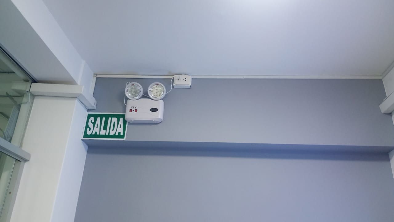 Techo del pasillo con luces de emergencia y un letrero verde de salida