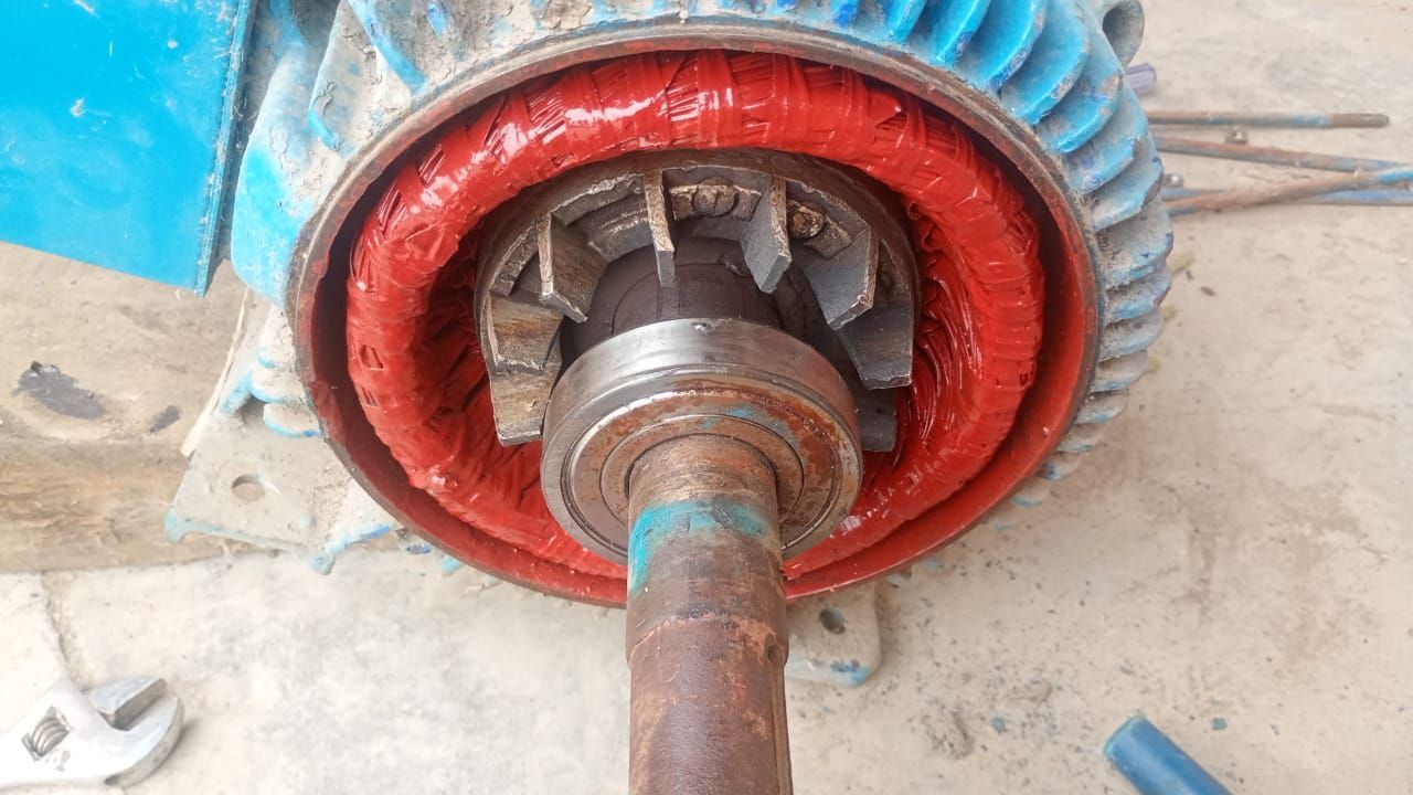 Primer plano de un cubo de rueda industrial rojo y azul con un eje y pernos oxidados.
