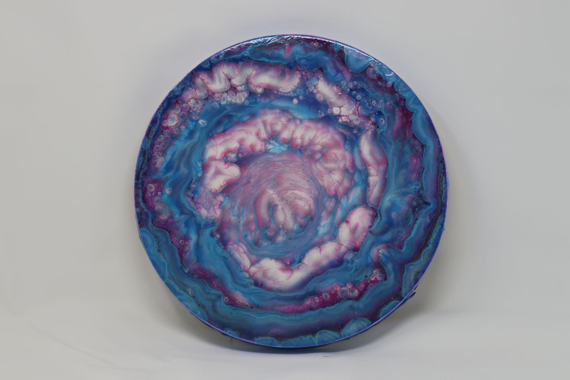 Circular blue and pink abstract swirl artwork on a light background
