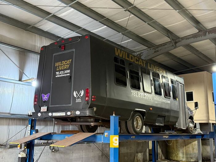 Black welded utility trailer on a blue lift in an industrial garage | JRJ Tire & Service