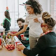 Friends chatting and reaching for drinks at a festive party table with decorations and red cups