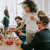 Friends chatting and reaching for drinks at a festive party table with decorations and red cups