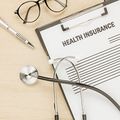 Health insurance form with stethoscope, pen, and glasses on a desk