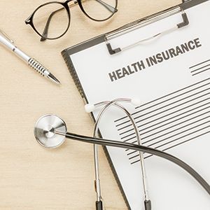 Health insurance form with stethoscope, pen, and glasses on a desk