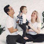 Smiling family sitting on the floor, playing with a toddler in a bright white room