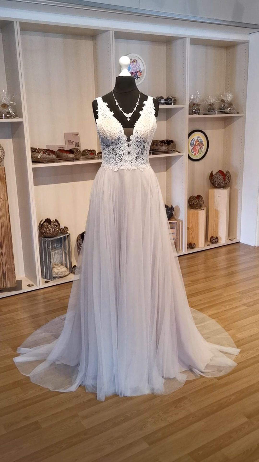 Weißes Abendkleid aus Spitze mit langem, fließendem Rock, ausgestellt an einer Schaufensterpuppe in einem Boutique-Showroom