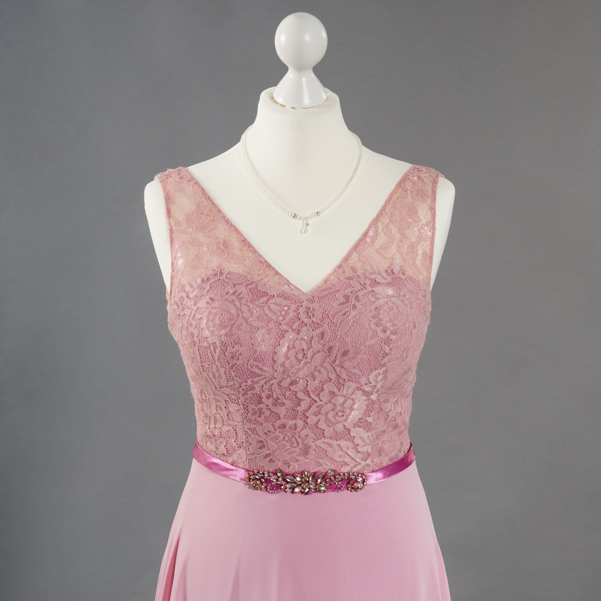 Rosa ärmelloses Spitzenkleid an einer Schaufensterpuppe mit einem juwelenbesetzten Taillengürtel