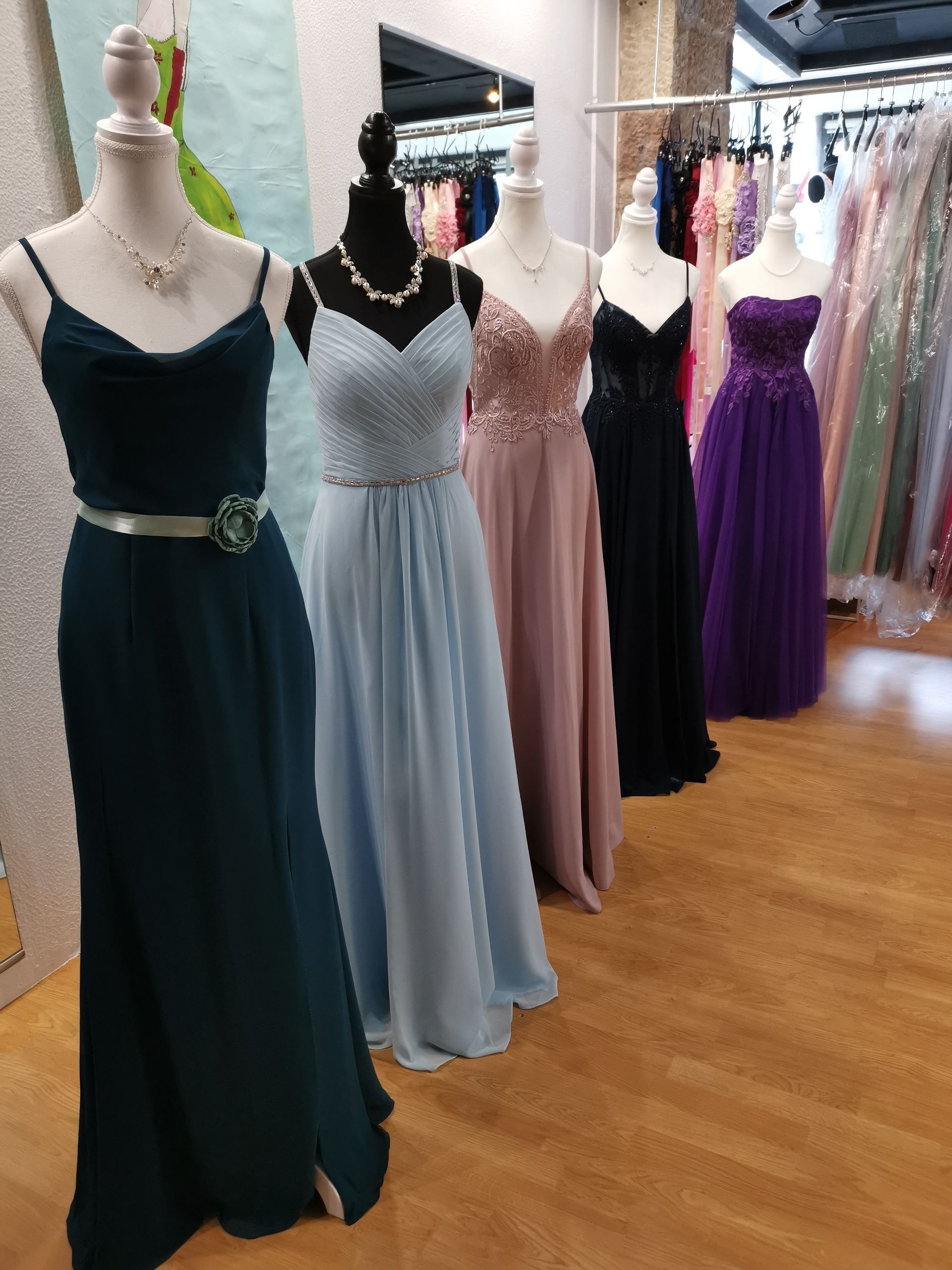 Festliche Kleider an Schaufensterpuppen in einer Boutique, in Türkis, Silber, Rosa, Schwarz und Lila.