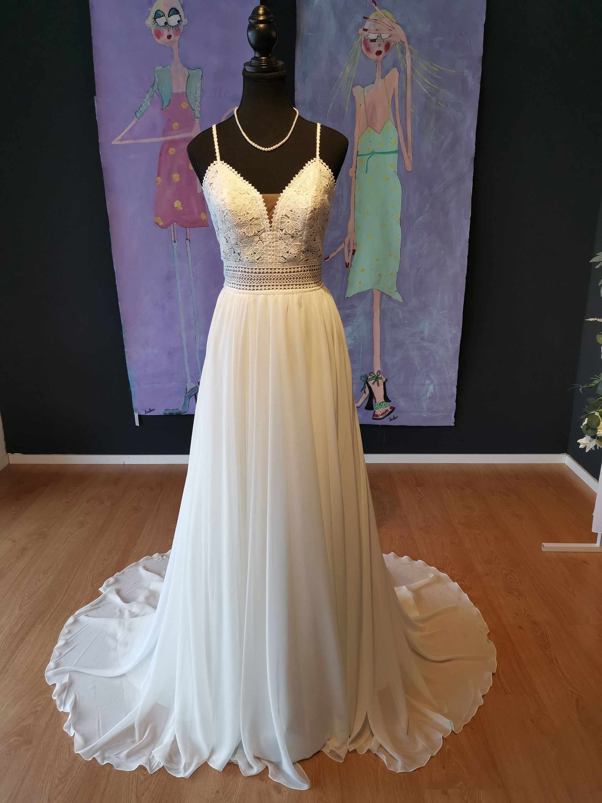 Cremefarbenes, trägerloses Kleid an einer Schaufensterpuppe in einer Boutique-Auslage, mit fließendem Tüllrock und Schleppe.