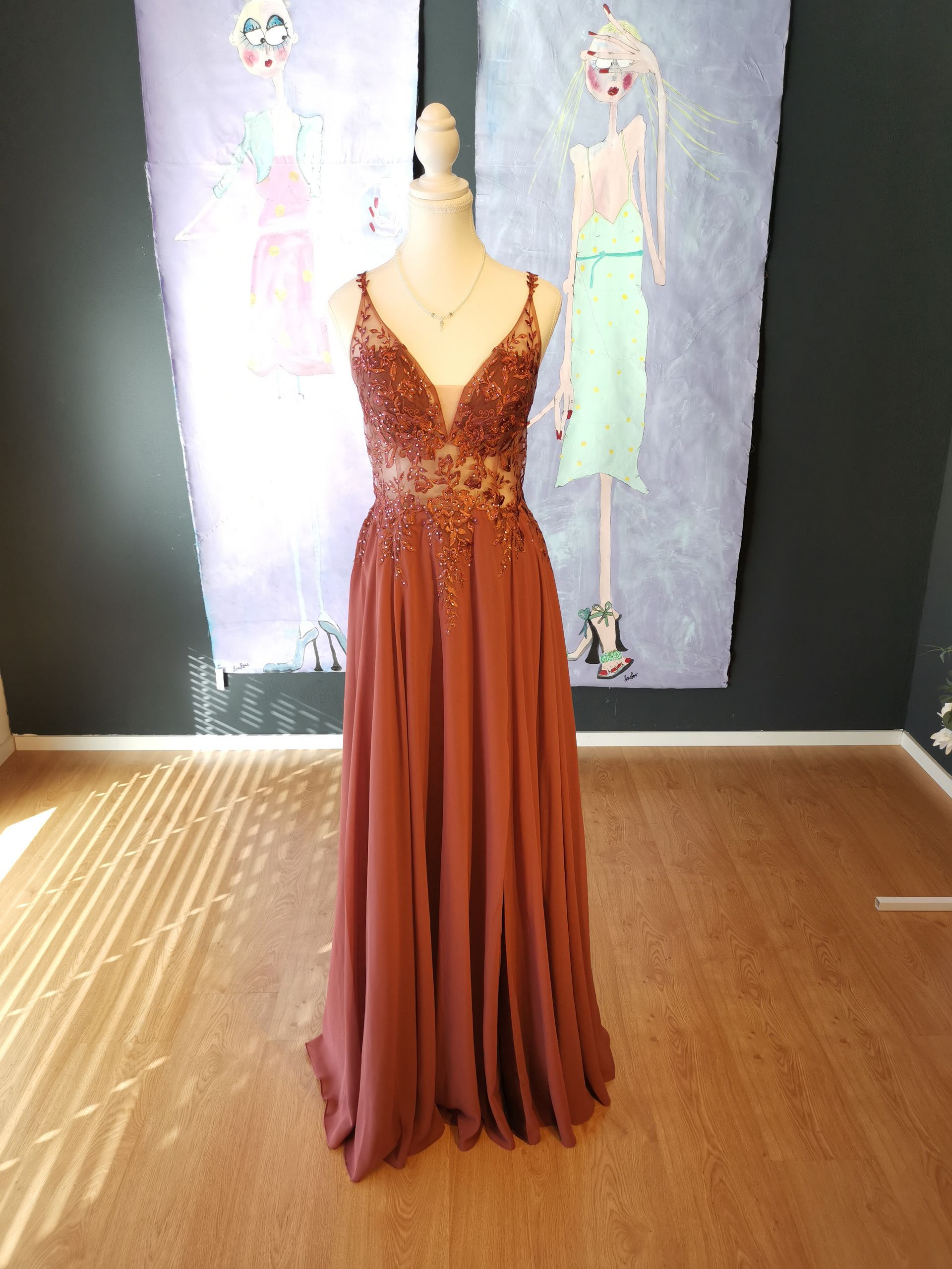 Rostfarbenes, paillettenbesetztes Abendkleid, ausgestellt an einer Schaufensterpuppe in einer Boutique oder einem Showroom.