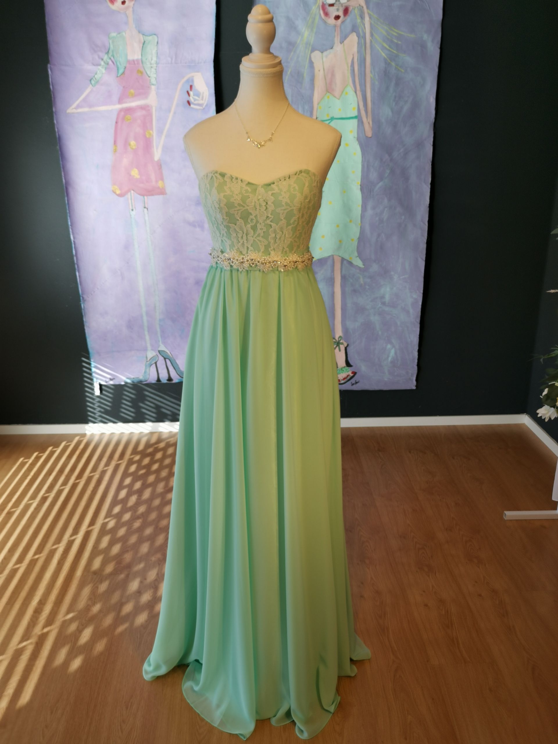Mintgrünes, trägerloses Kleid an einer Schaufensterpuppe vor einem pastellfarbenen Modeillustrationshintergrund