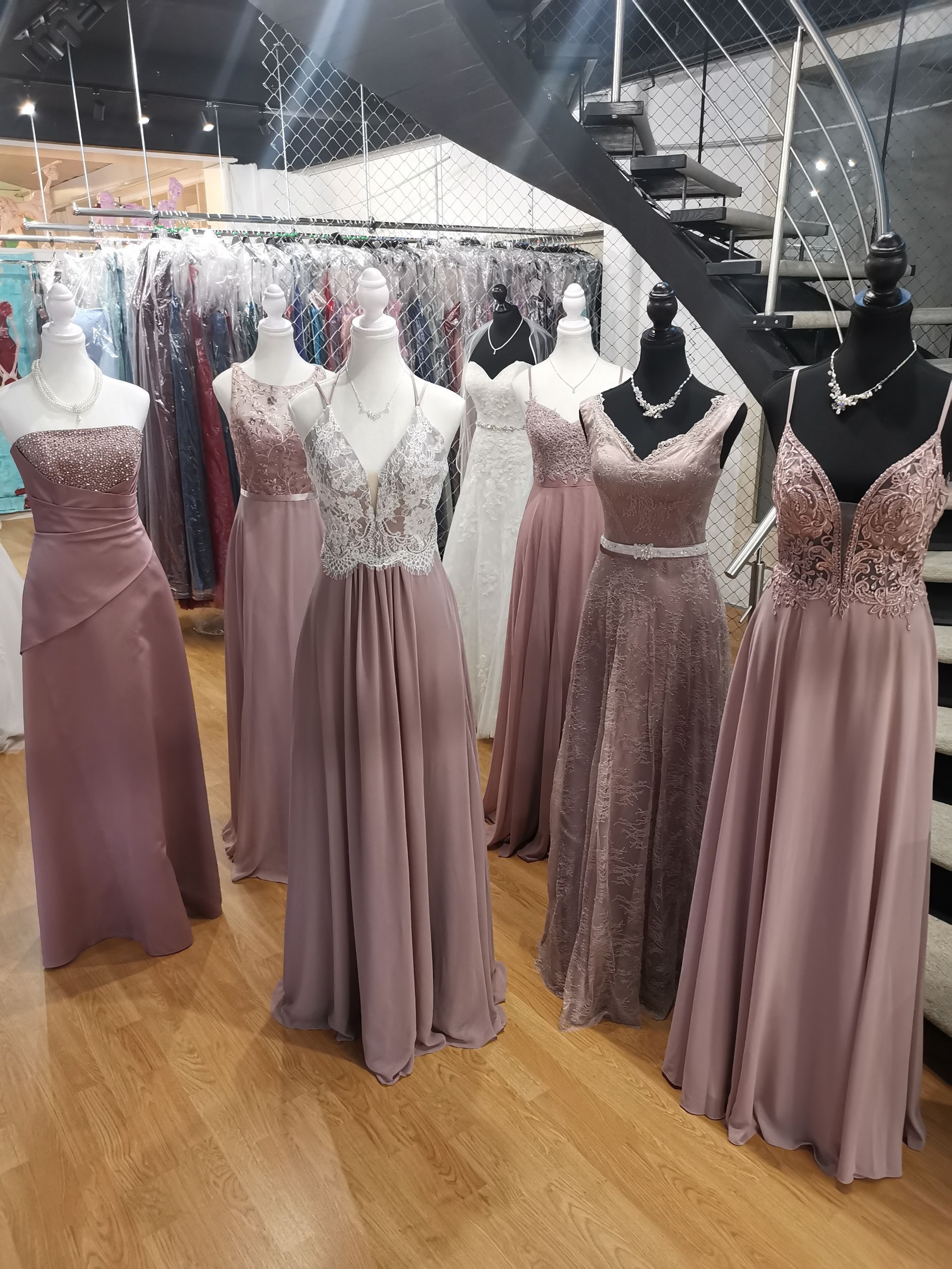 Schaufensterpuppen präsentieren in einem Boutique-Showroom Abendkleider in den Farben Mauve und Rosé.